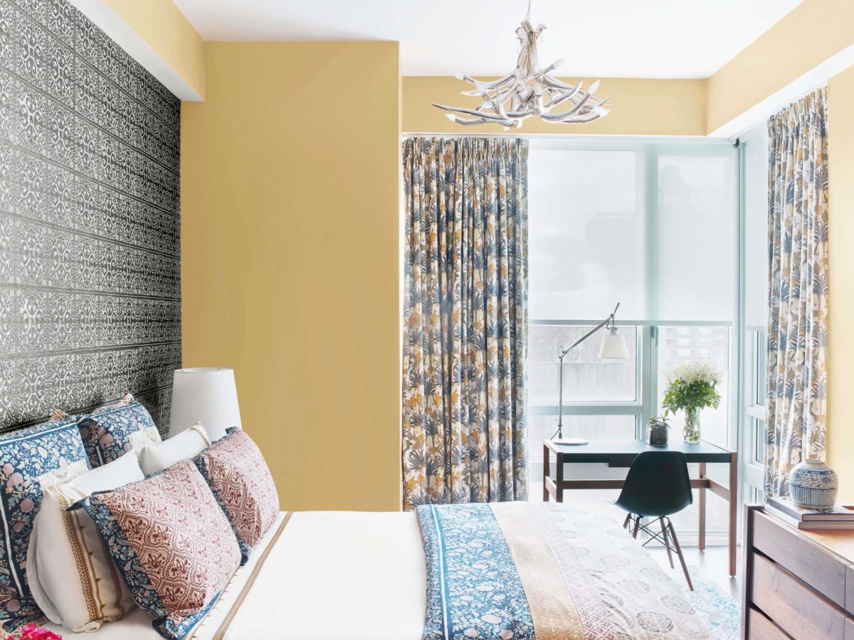 yellow bedroom with colorful bed and bright window