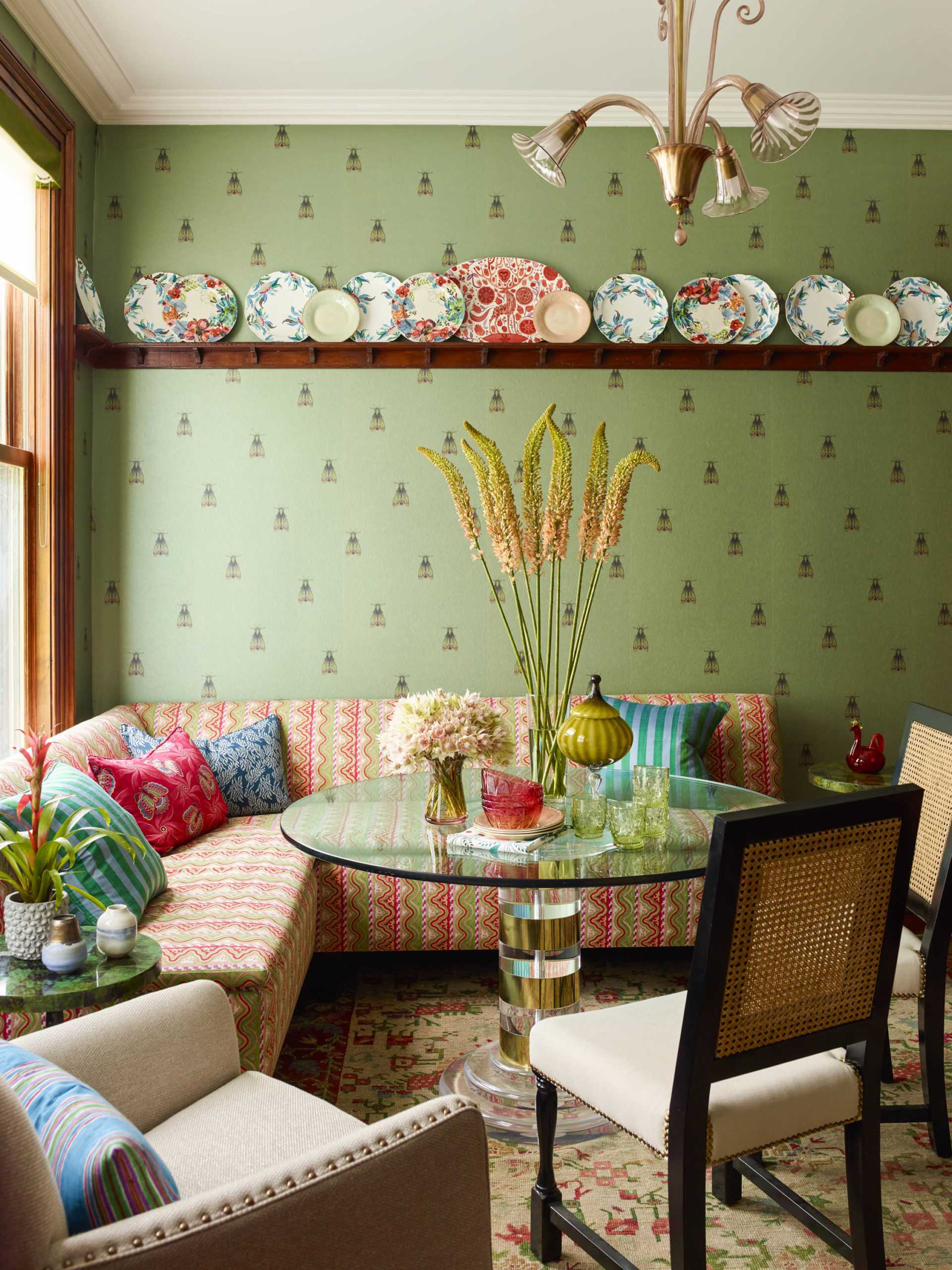 eclectic breakfast nook with green wallpaper and colorful seating and antique plates