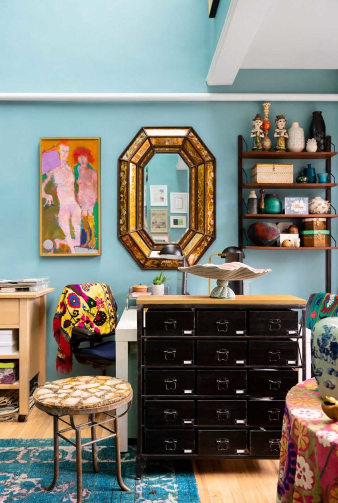 Colorful interior design studio with gold mirror and black storage cabinets with art everywhere